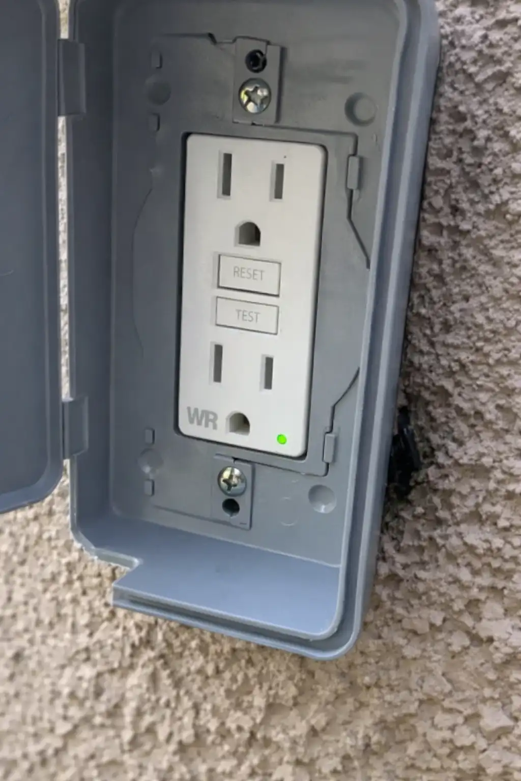 GFCI outlet installed on an exterior stucco wall, a common component in home electrical safety